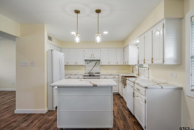 kitchen with dark hardwood / wood-style floors, white appliances, light stone countertops, a kitchen island, and white cabinets