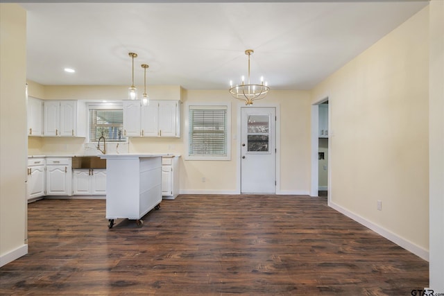 kitchen with white cabinetry, a notable chandelier, dark hardwood / wood-style flooring, hanging light fixtures, and sink