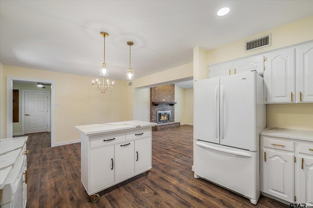 kitchen with a fireplace, pendant lighting, white cabinetry, dark wood-type flooring, and white refrigerator