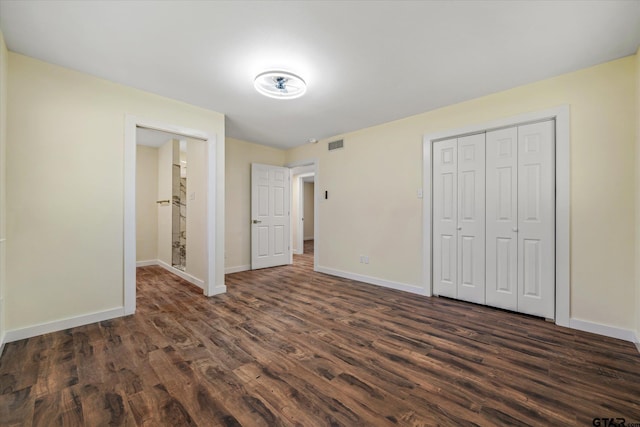 unfurnished bedroom with dark wood-type flooring and a closet