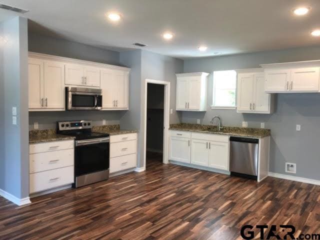 kitchen with white cabinets, dark wood-type flooring, and appliances with stainless steel finishes