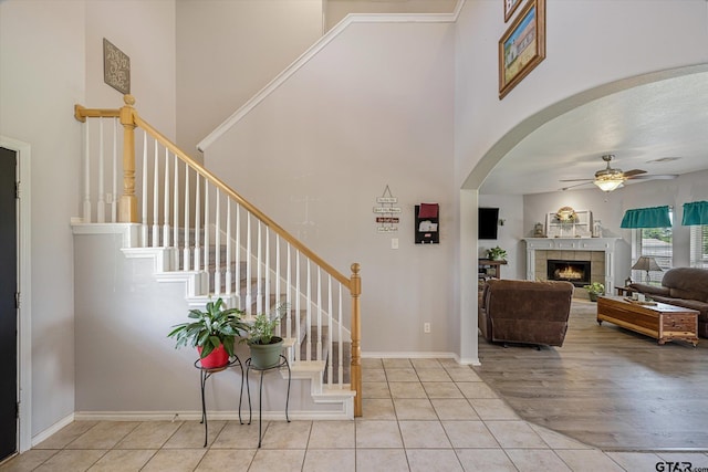 entryway featuring ceiling fan, a fireplace, a towering ceiling, and light hardwood / wood-style floors