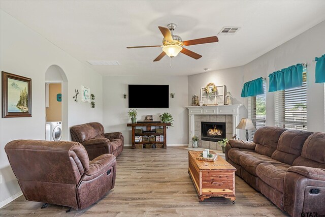 living room featuring a fireplace, ceiling fan, washer and clothes dryer, and wood-type flooring