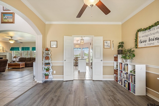 entrance foyer featuring ceiling fan with notable chandelier, wood-type flooring, and ornamental molding