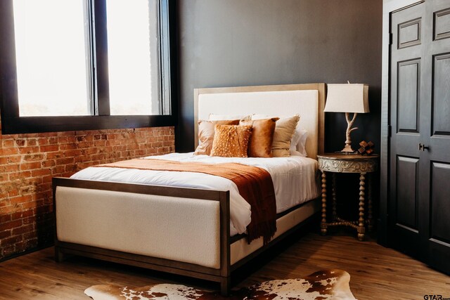 bedroom with brick wall and wood-type flooring