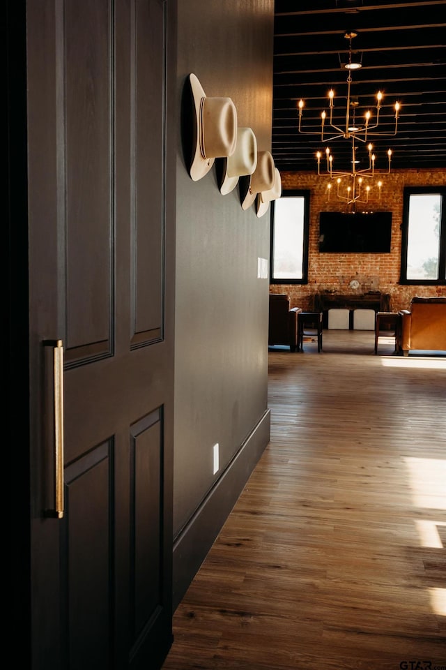 hall featuring hardwood / wood-style flooring and brick wall