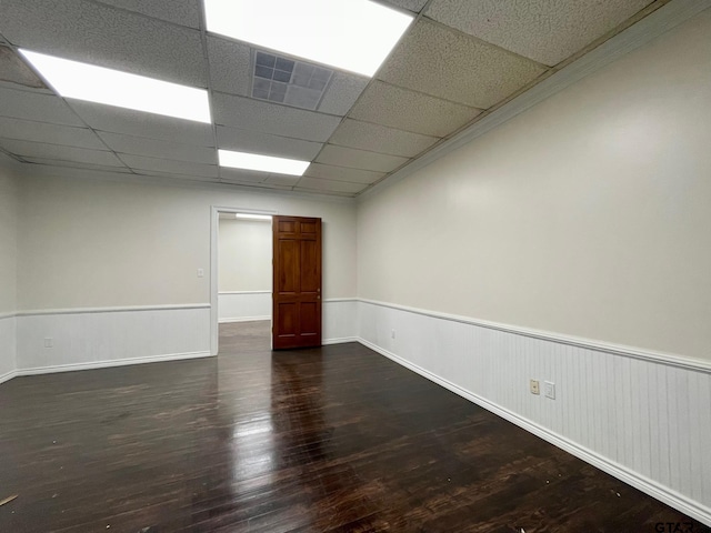 spare room featuring dark hardwood / wood-style flooring and a drop ceiling