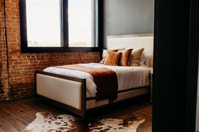 bedroom with brick wall and hardwood / wood-style floors