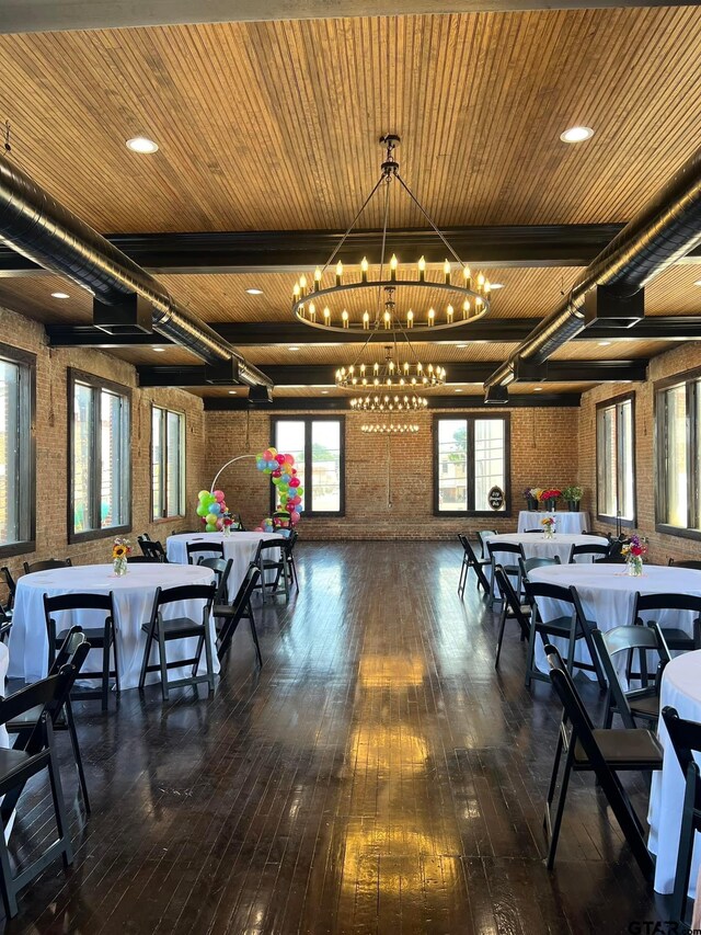 dining space featuring beam ceiling, brick wall, dark hardwood / wood-style flooring, wooden ceiling, and a chandelier