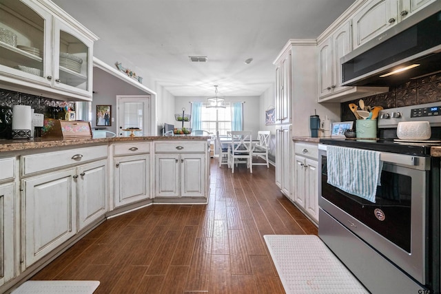 kitchen with a peninsula, visible vents, appliances with stainless steel finishes, dark wood finished floors, and glass insert cabinets