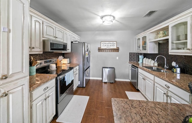 kitchen with visible vents, glass insert cabinets, appliances with stainless steel finishes, dark wood-type flooring, and a sink