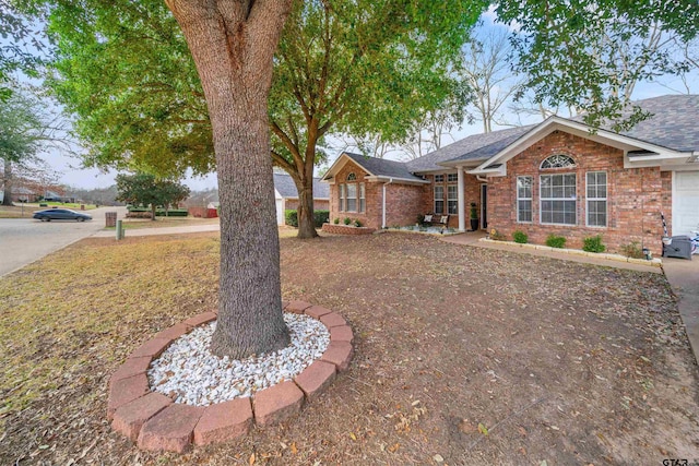 ranch-style home featuring brick siding and roof with shingles