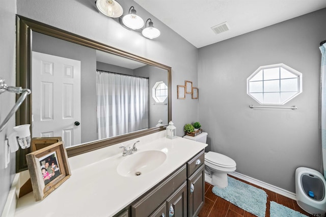 bathroom featuring baseboards, visible vents, toilet, wood finished floors, and vanity