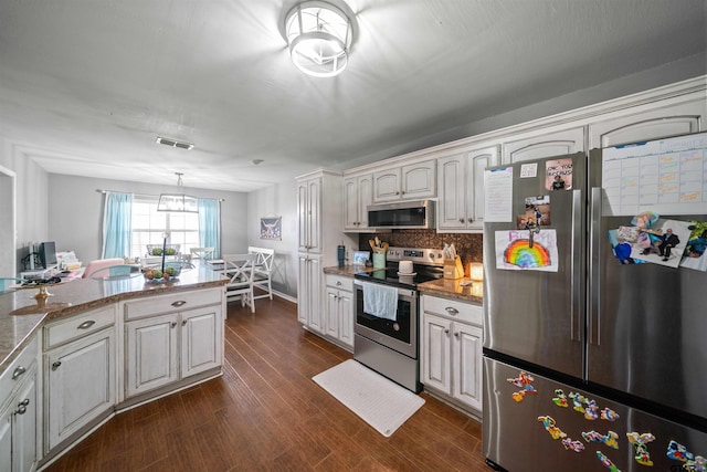 kitchen featuring dark wood-style flooring, visible vents, appliances with stainless steel finishes, backsplash, and decorative light fixtures