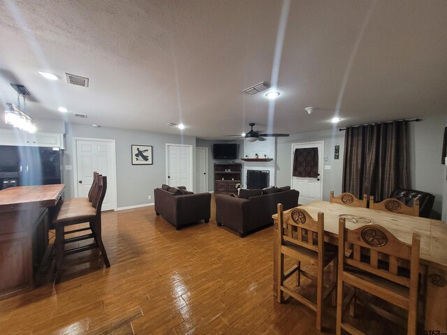 living room with wood-type flooring, a fireplace, and ceiling fan