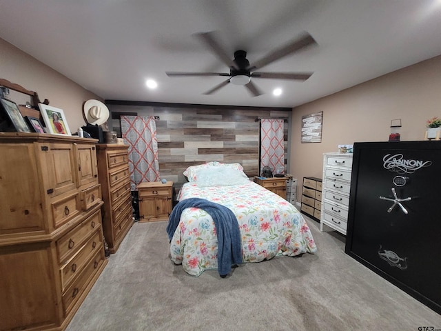 bedroom featuring ceiling fan, light carpet, and wood walls