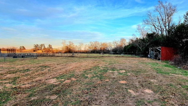 yard at dusk featuring a rural view