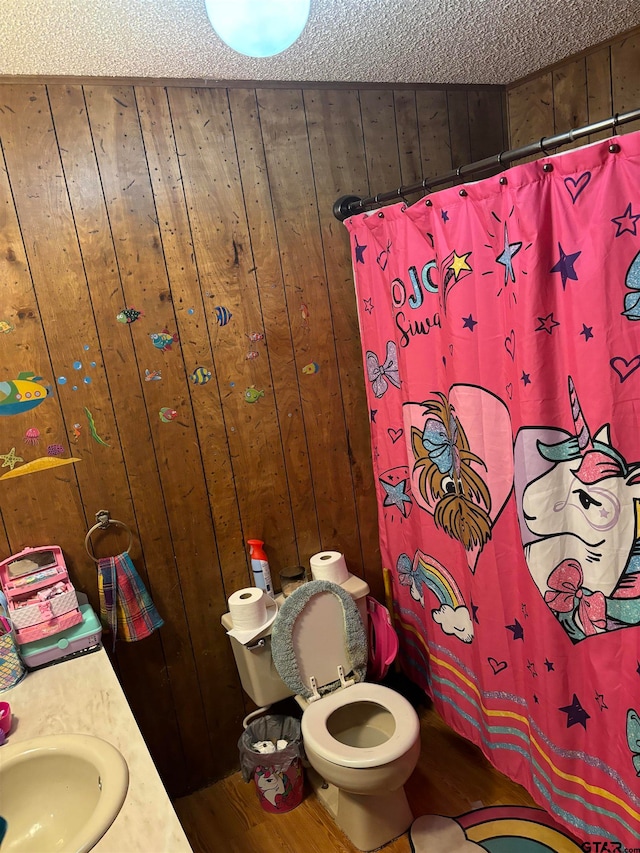 bathroom featuring wood walls, wood-type flooring, and a textured ceiling