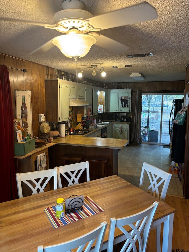 kitchen featuring wood walls, ceiling fan, a textured ceiling, and kitchen peninsula