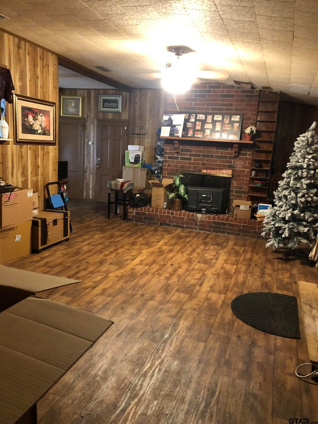 living room with hardwood / wood-style floors, lofted ceiling, a brick fireplace, and wooden walls