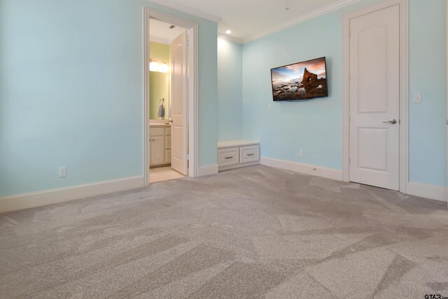 unfurnished bedroom featuring ensuite bathroom, crown molding, and light colored carpet