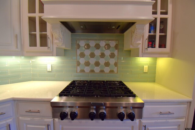 kitchen with tasteful backsplash, white cabinetry, ventilation hood, and stainless steel gas cooktop