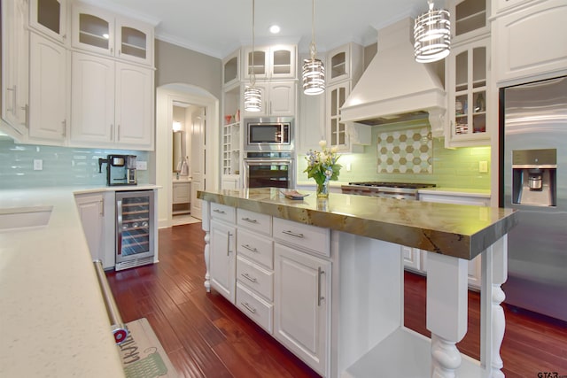 kitchen with wine cooler, white cabinetry, built in appliances, and hanging light fixtures