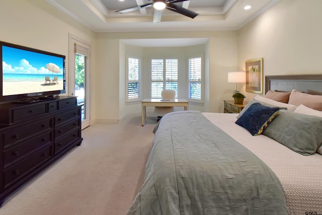 carpeted bedroom with a tray ceiling, ceiling fan, and ornamental molding