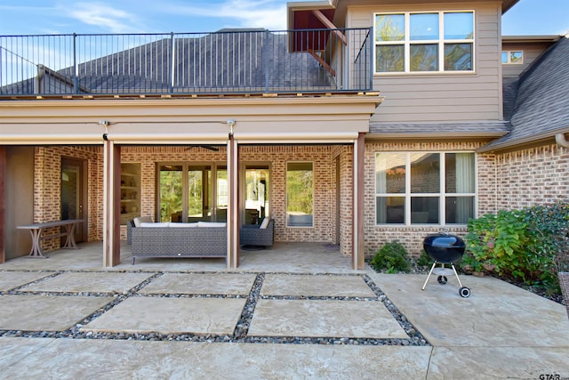 back of property with outdoor lounge area, a balcony, and a patio area