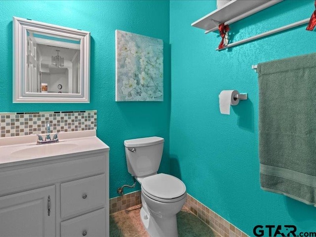 bathroom featuring toilet, vanity, and tasteful backsplash