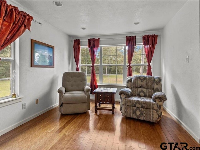 sitting room with hardwood / wood-style flooring, a textured ceiling, and a healthy amount of sunlight