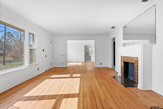 2444 Sunnybrook Dr, Tyler, TX 75701 - unfurnished living room featuring ornamental molding, light hardwood / wood-style flooring, and a tile fireplace