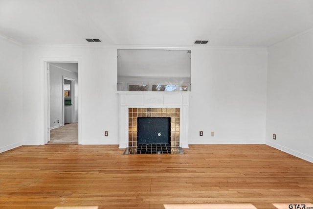 2444 Sunnybrook Dr, Tyler, TX 75701 - unfurnished living room featuring a tiled fireplace, ornamental molding, and light hardwood / wood-style flooring