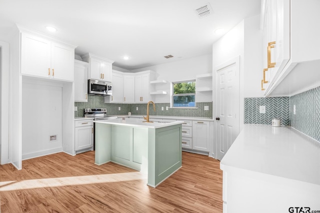 kitchen featuring open shelves, light wood finished floors, appliances with stainless steel finishes, and light countertops