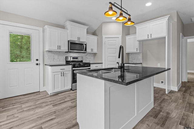 kitchen with tasteful backsplash, pendant lighting, a kitchen island with sink, and stainless steel appliances