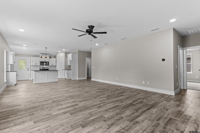 unfurnished living room featuring ceiling fan and light hardwood / wood-style floors