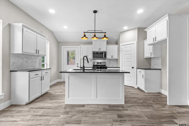 kitchen featuring a center island with sink, appliances with stainless steel finishes, pendant lighting, sink, and white cabinets