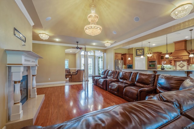 3072 Yasmeen Cir, Flint, TX 75762 - living room featuring crown molding, light wood finished floors, a tile fireplace, arched walkways, and baseboards