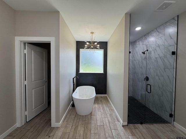 18268 US Jones Dr, Tyler, TX 75705 - bathroom with wood finished floors, a soaking tub, a stall shower, and a chandelier