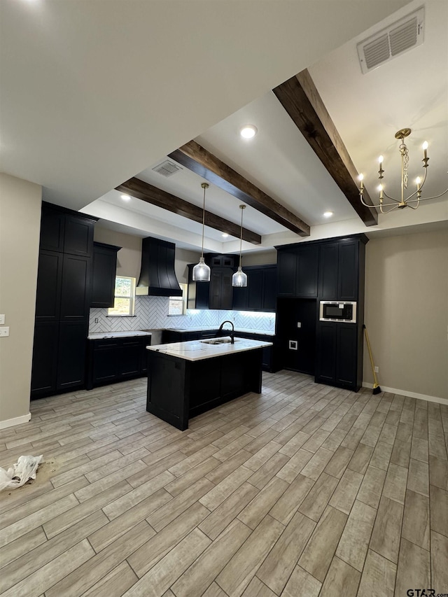 18268 US Jones Dr, Tyler, TX 75705 - kitchen featuring custom range hood, dark cabinets, backsplash, a chandelier, and a kitchen island with sink