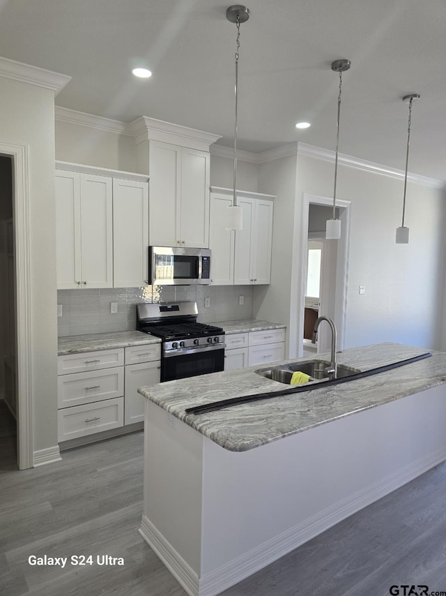 kitchen with white cabinetry, sink, hanging light fixtures, and appliances with stainless steel finishes