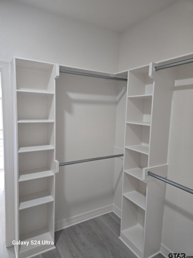 walk in closet with dark wood-type flooring