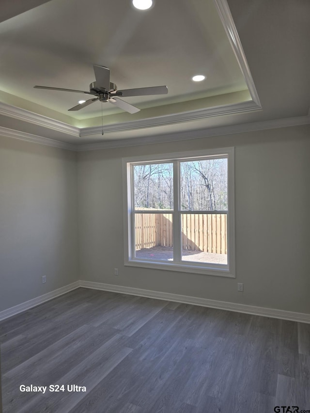 empty room featuring crown molding, dark hardwood / wood-style floors, ceiling fan, and a tray ceiling