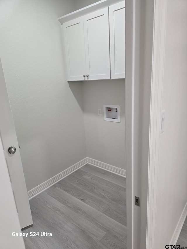 laundry area with washer hookup, cabinets, and light wood-type flooring