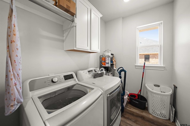 clothes washing area with washer and clothes dryer, dark hardwood / wood-style floors, and cabinets