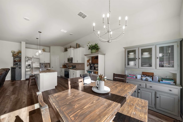 dining area with sink, dark wood-type flooring, and an inviting chandelier