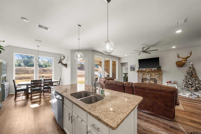 kitchen featuring white cabinetry, dark wood-type flooring, stainless steel dishwasher, decorative light fixtures, and a kitchen island with sink