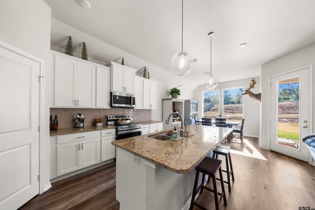 kitchen with sink, stainless steel appliances, decorative light fixtures, a kitchen island with sink, and white cabinets