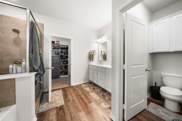 bathroom with hardwood / wood-style floors, vanity, a shower with shower door, and toilet