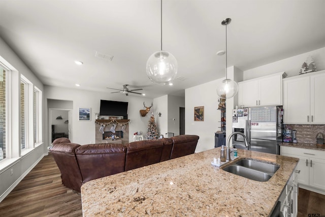 kitchen with pendant lighting, a kitchen island with sink, white cabinets, sink, and stainless steel fridge with ice dispenser